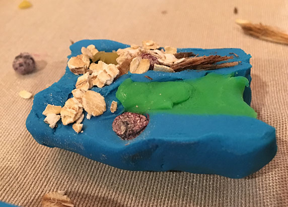 oatmeal chunks are added to the playdoh cross section with the bits of wood