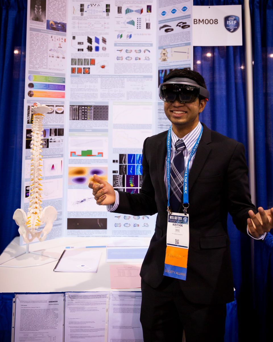 a young student in a suit and tie smiling while wearing VR goggles