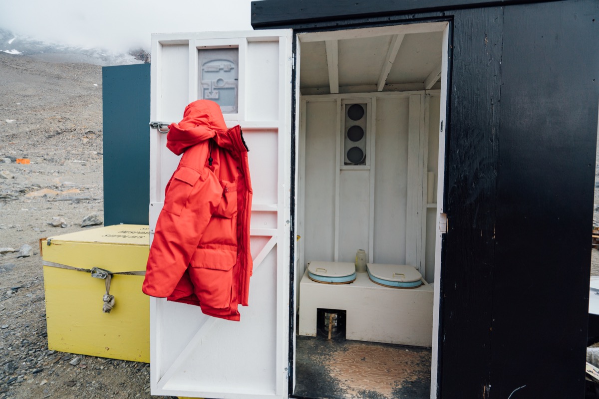 a port-o-john shed with the door open and a big puffy red coat hanging on it