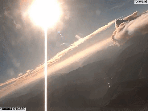 a gif of a time lapse video flying above mountains into areas of thick smoke