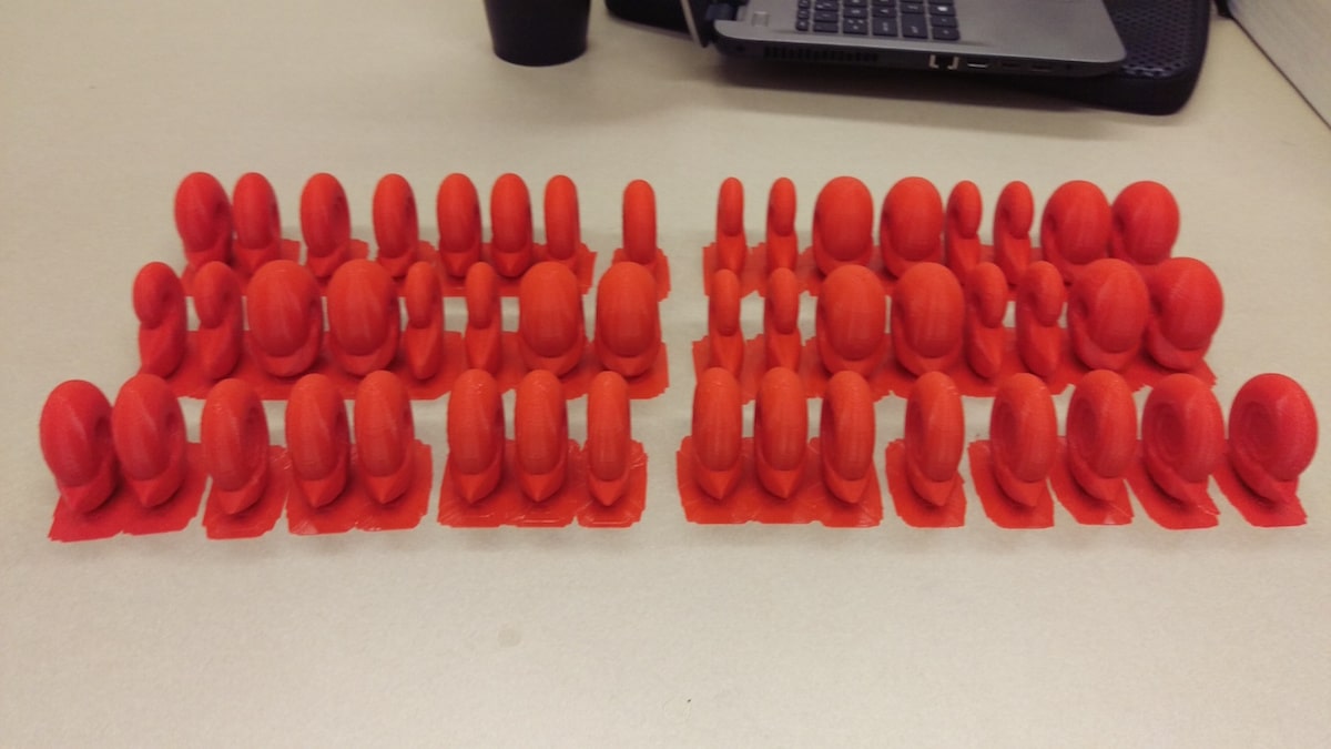 three rows of 3D printed ammonite shells of various shapes. they are all in a red plastic