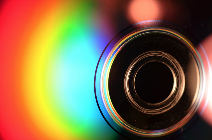 a close up of the bottom of a cd. with light shining on the surface, it shows a rainbow of shiny color