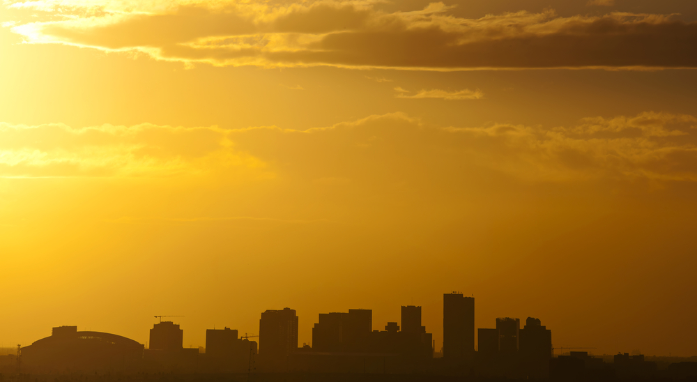 a city skyline under a hazy yellow, brown sunset