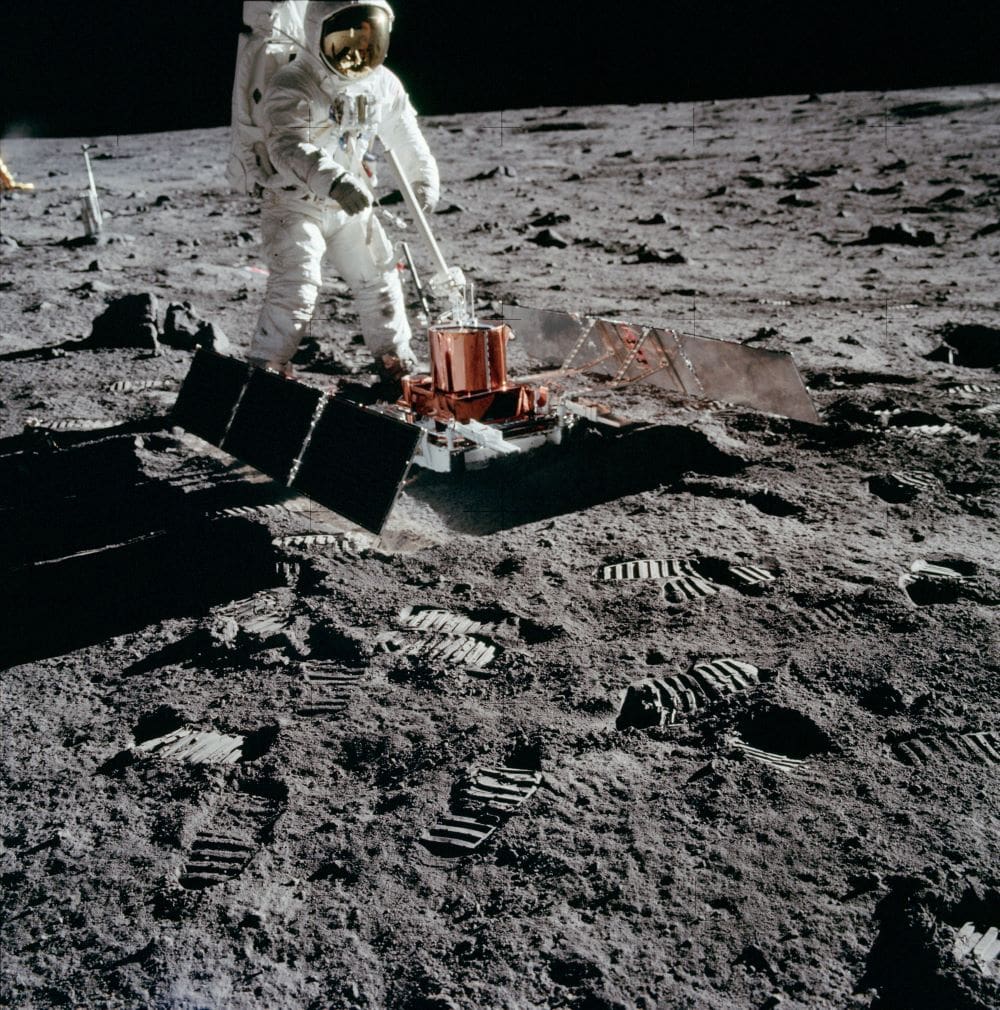 an astronaut uses mechanical equipment on the surface of the moon