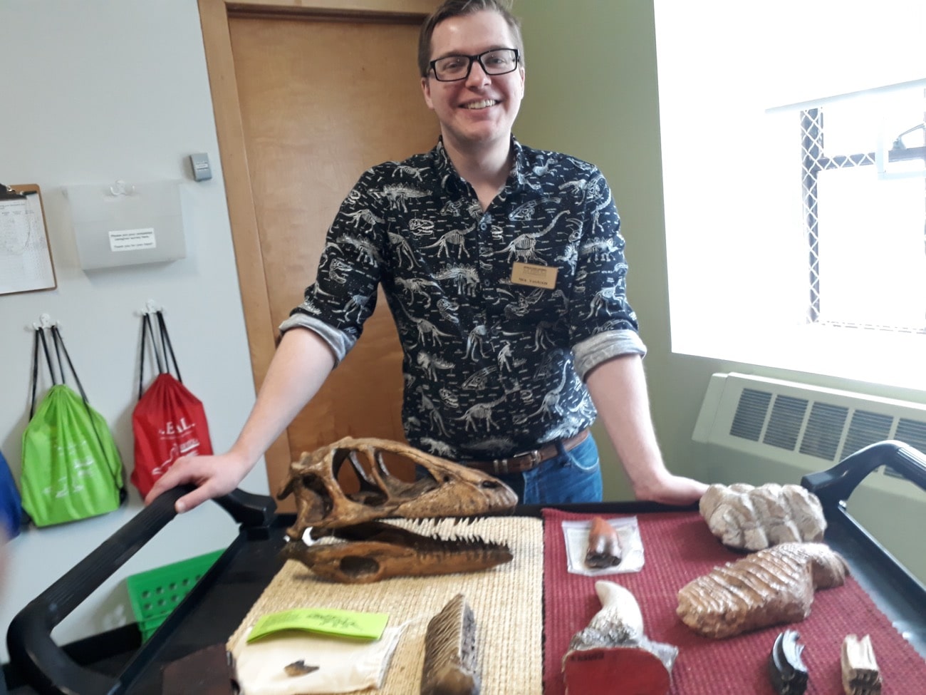 a man standing in front of a table with skeletons, including a small skull