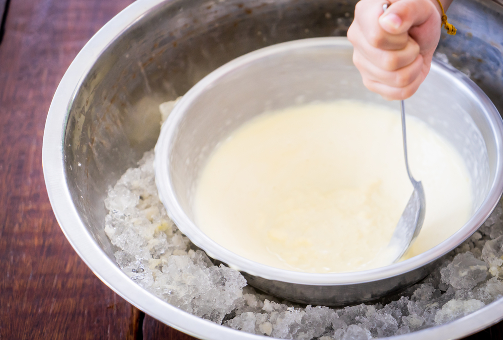 Children hand making home made ice cream with iced bowl. Spinning steel bowl for making Vanilla Ice Cream.