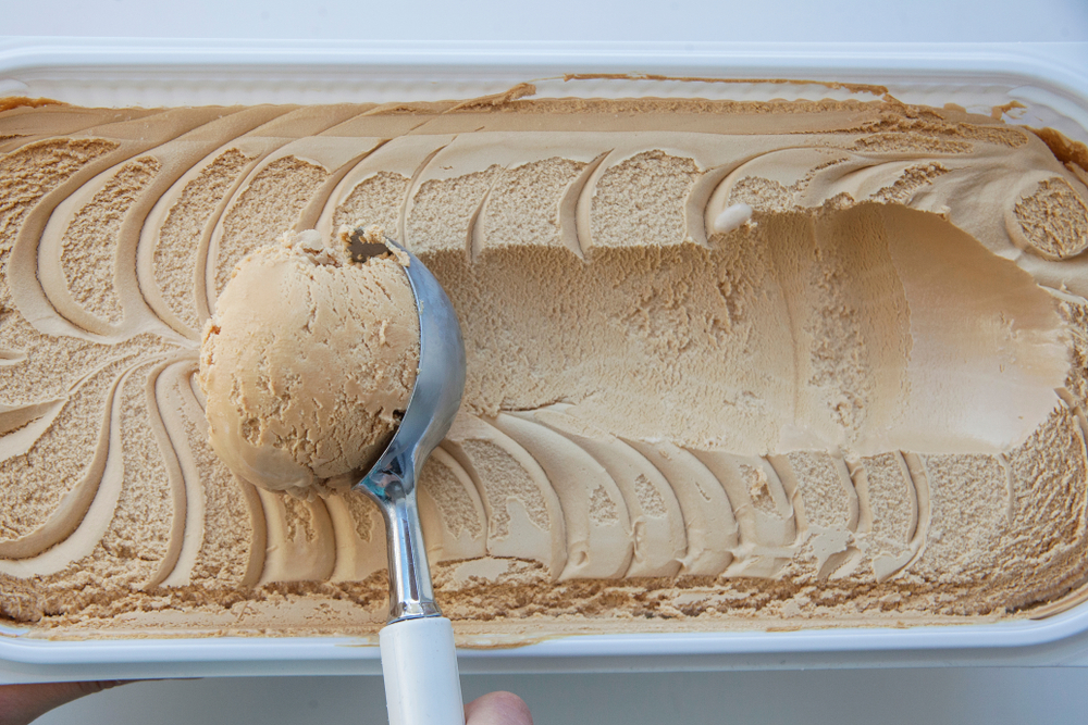 tan-colored ice cream. an ice cream scooper scoops a big helping of the ice cream