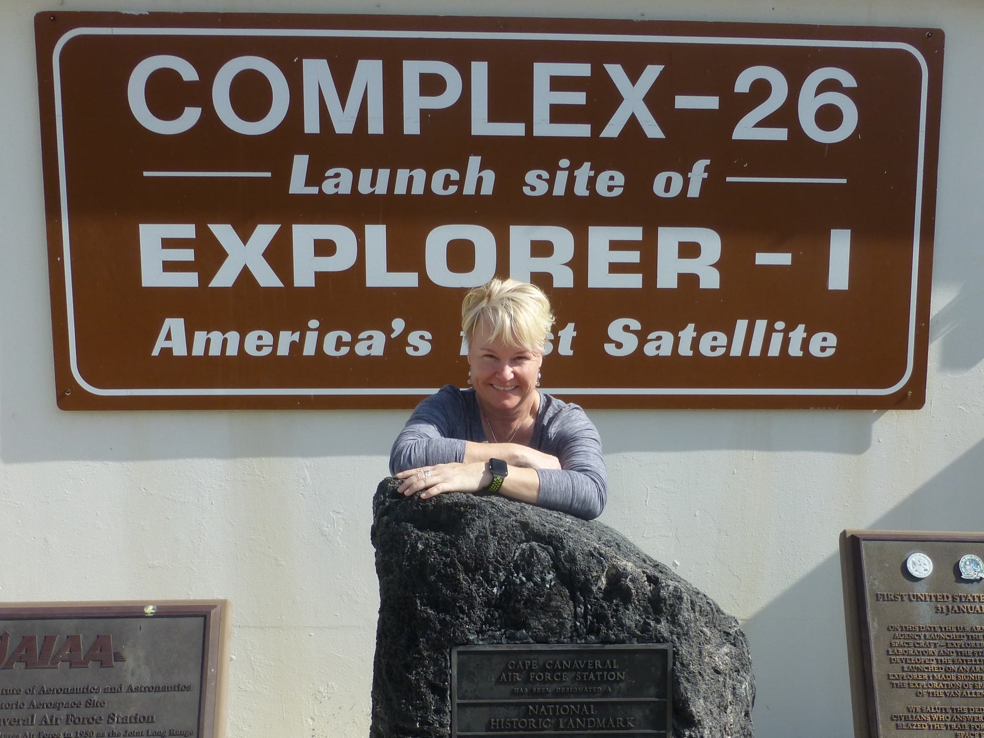 a woman stands in front of a sign that says 'complex-26 launch site of explorer - I America's first satellite