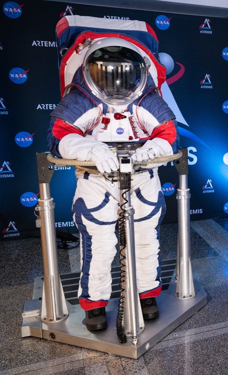 a full body shot of a space suit that is color red, blue, and white. on the back is a large pack