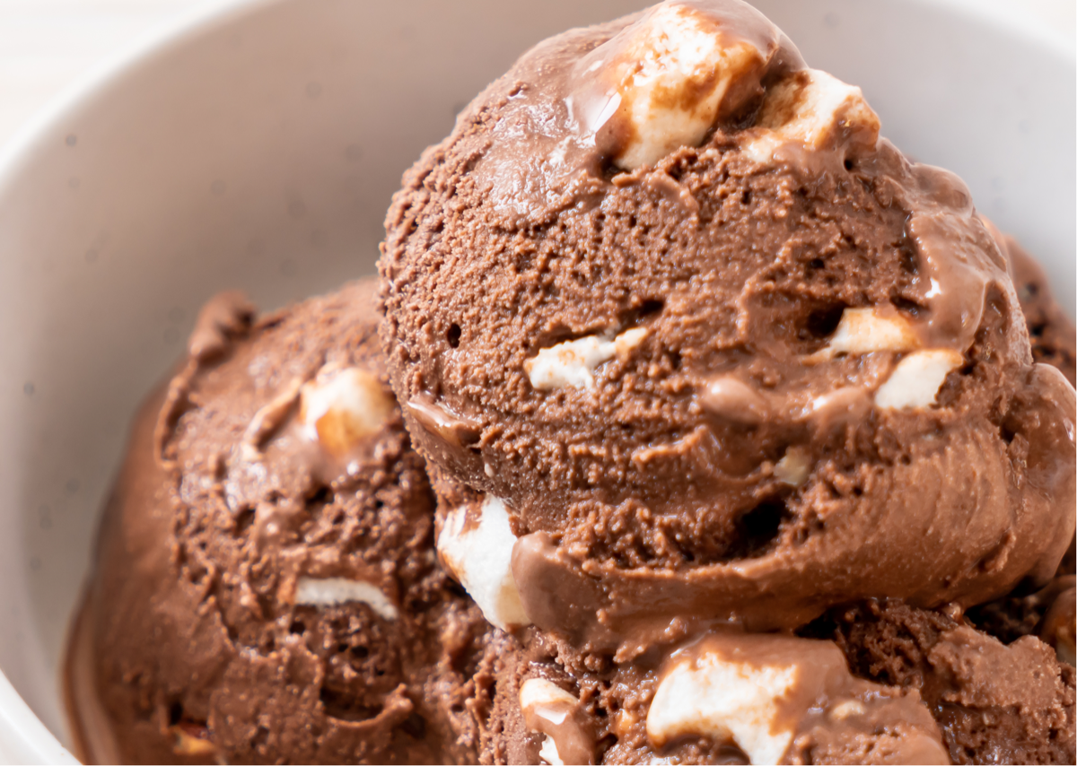 a close up on a few scoops of rocky road ice cream -- with chocolate ice cream and marshmallow swirls