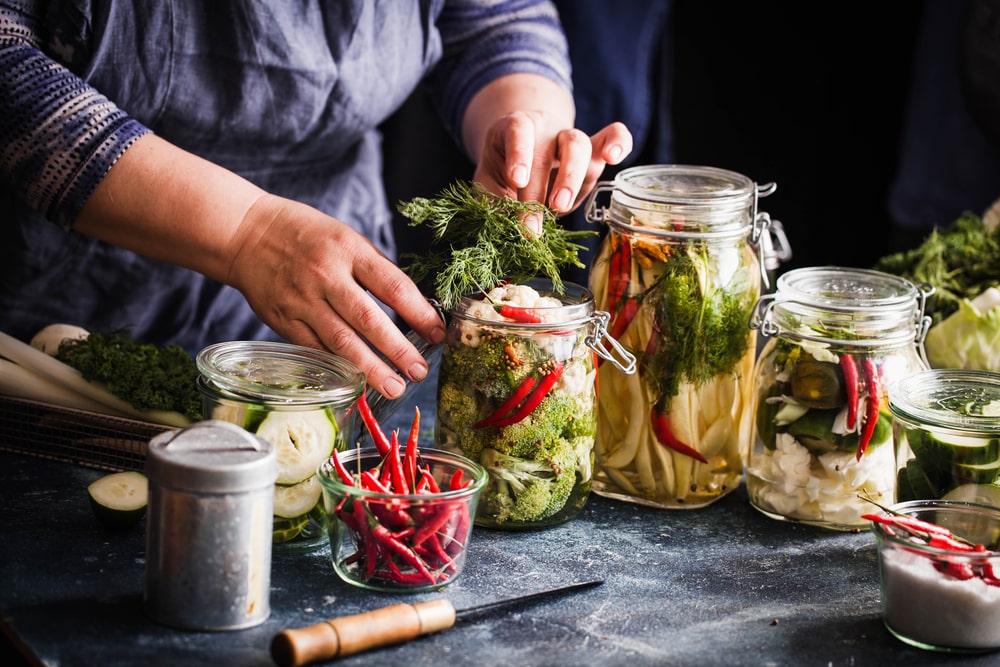 someone bottling jars of pickled foods on a table