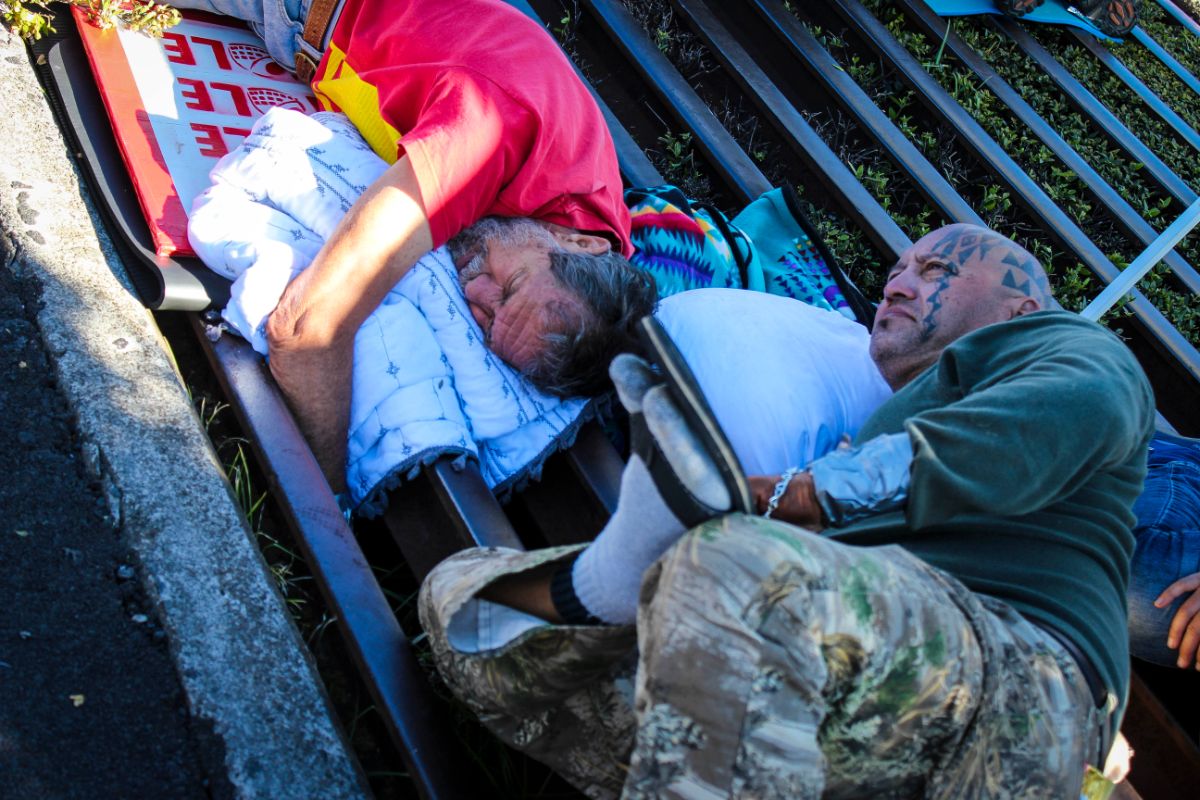 two men lie chained to a metal cattle grate