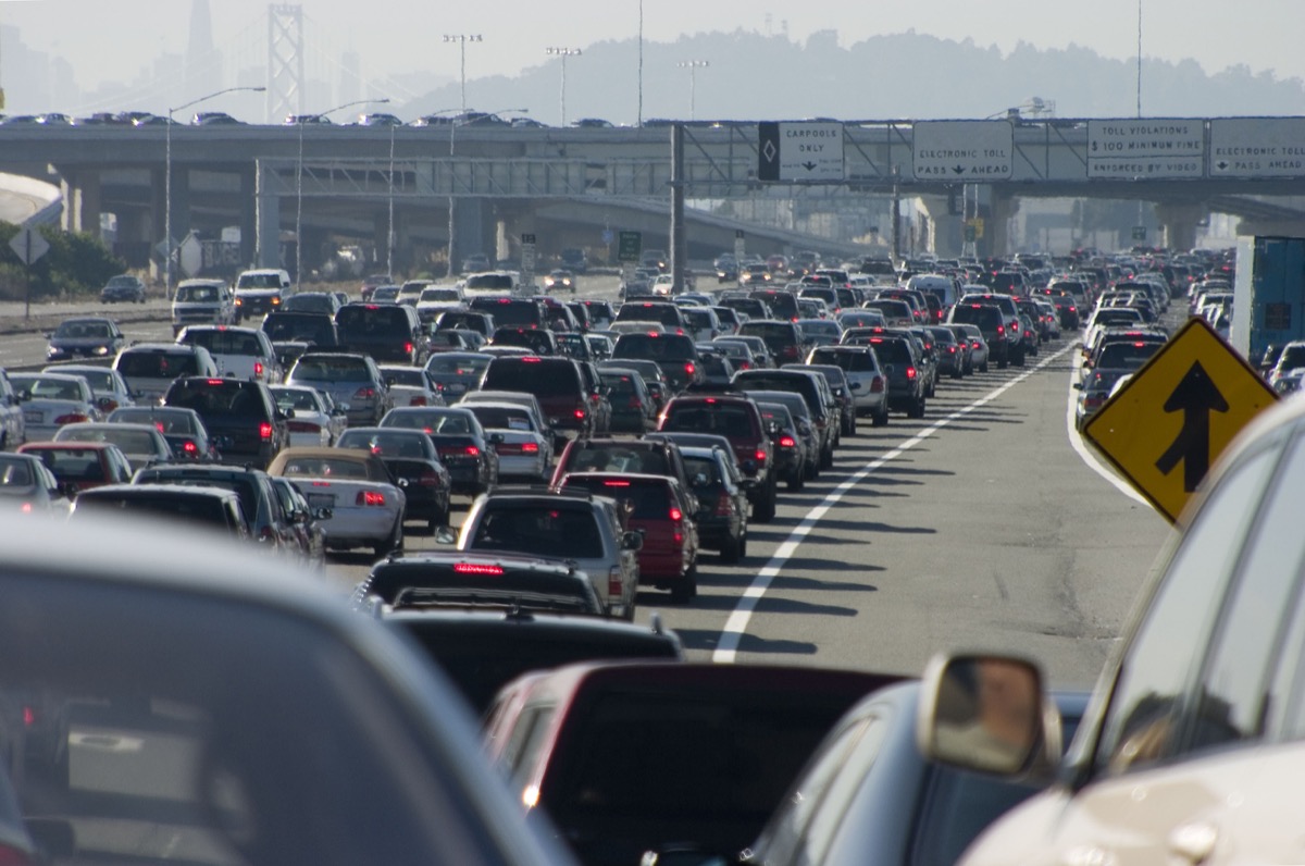 cars wait in traffic on a highway, with smoggy air in the background