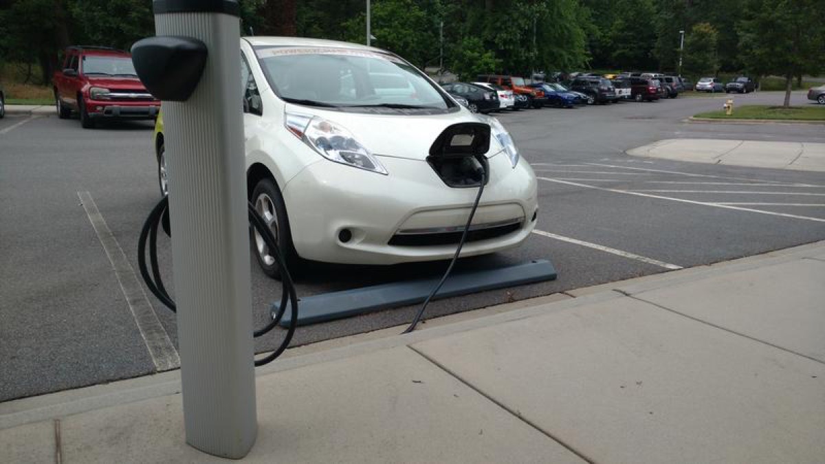 a white electric car is charging on a pump