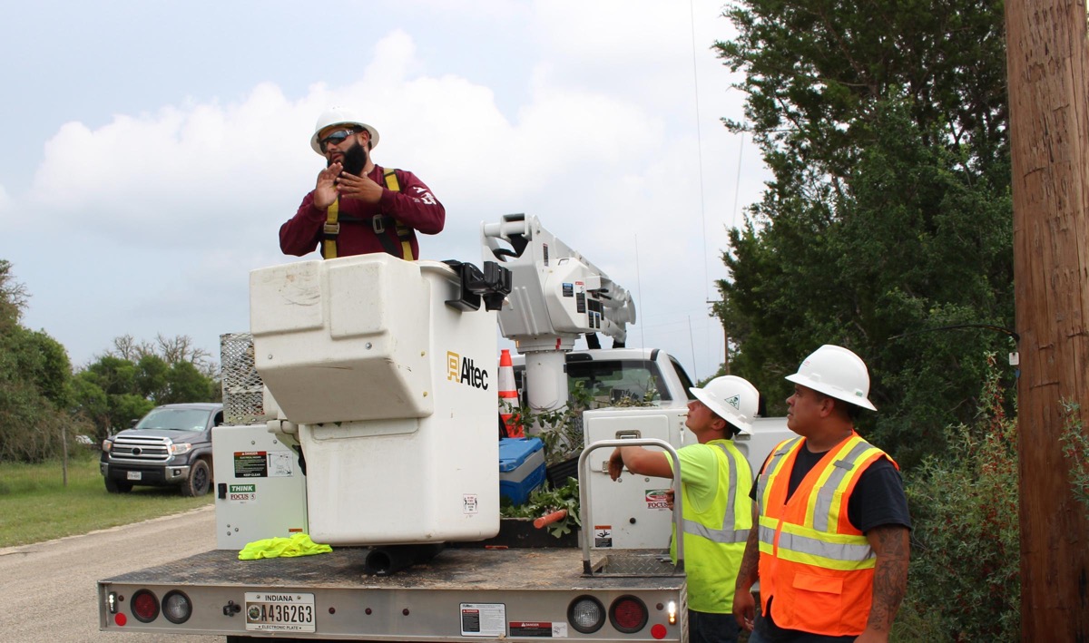 three construction workers get ready to go up a cherry picker in rural texas