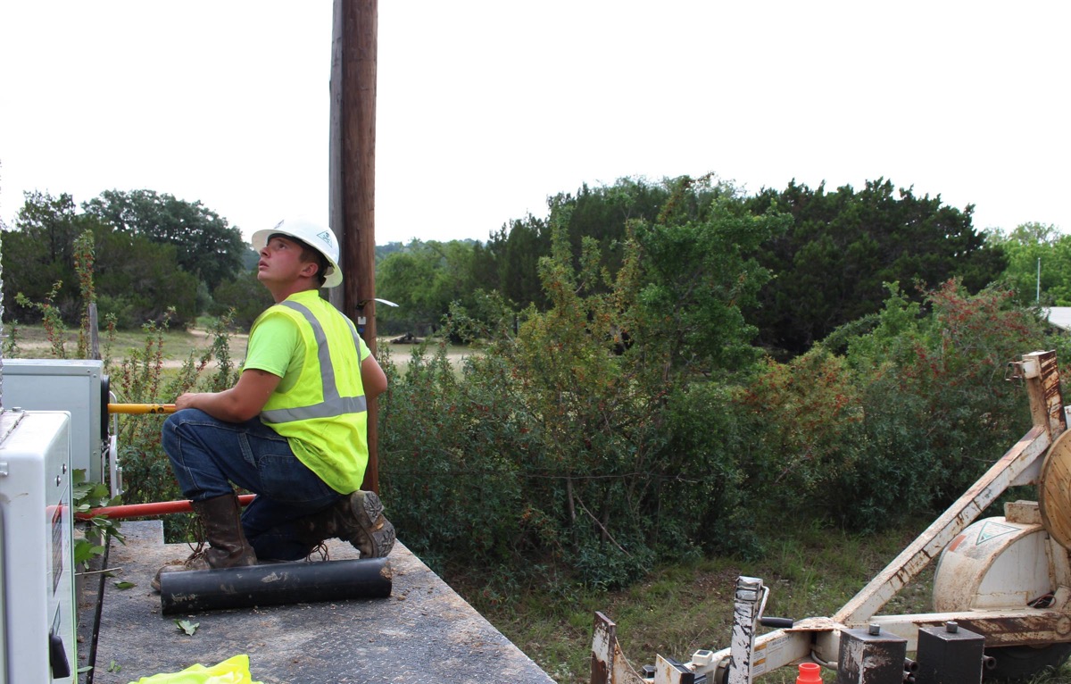 a man in a construction uniform looking up at the sky on the side of a road in rural texas