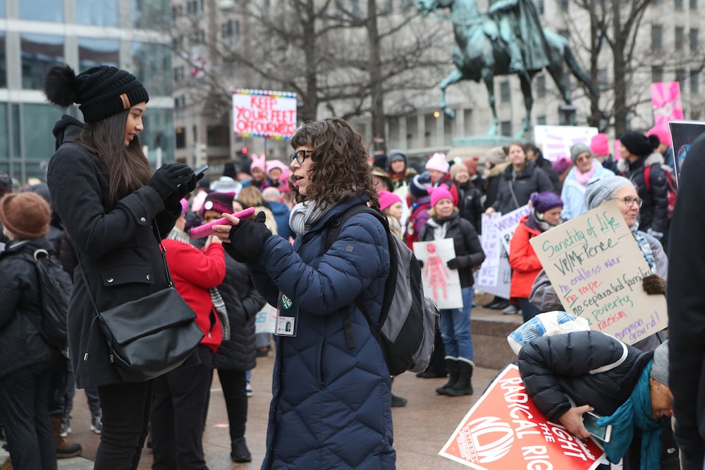 a woman interviews a young female protester at a women's march