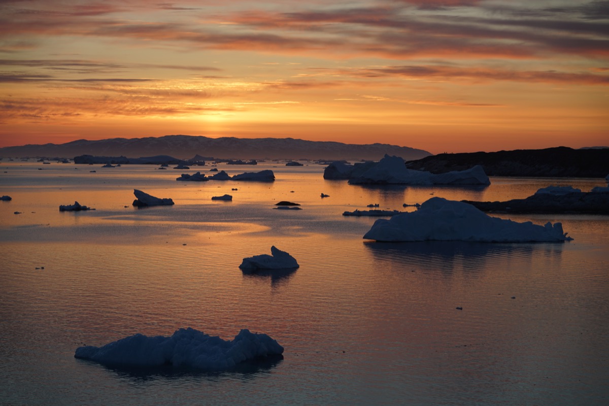 a sparse collection of icebergs underneath an orange sky