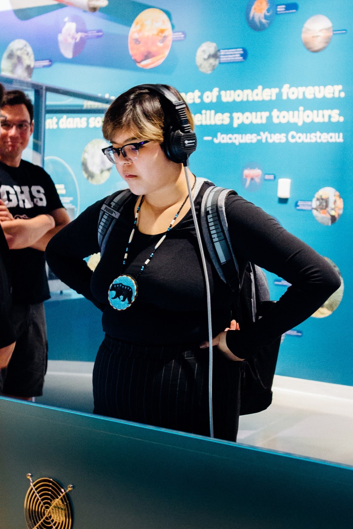 a student at a museum with headphones on listening to an exhibit