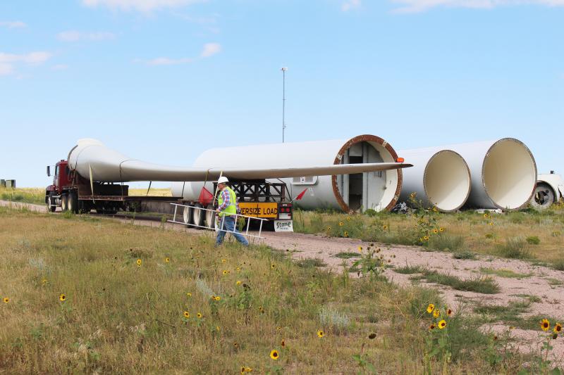 four giant wind turbine blades lay on their side on the ground