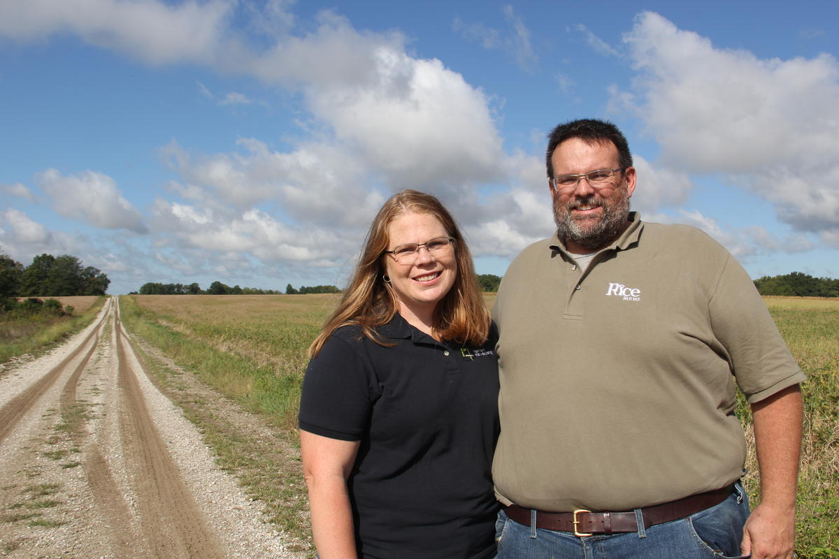 Couple stands in front of their farm 