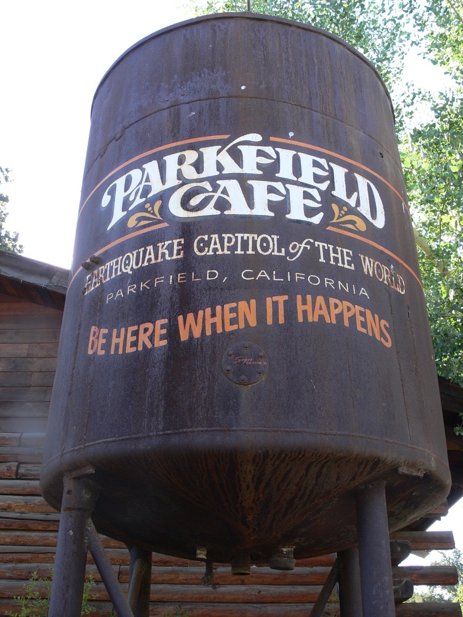 a water tower that says 'parkfield cafe, earthquake capitol of the world, be here when it happens'