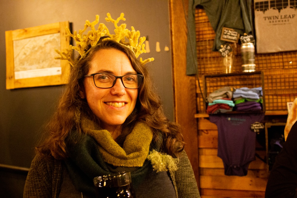 a woman wearing a crown made of brown pipecleaners than resemble a lichen