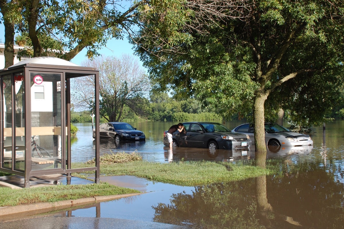 a person looks into a car in a flooded parking lot