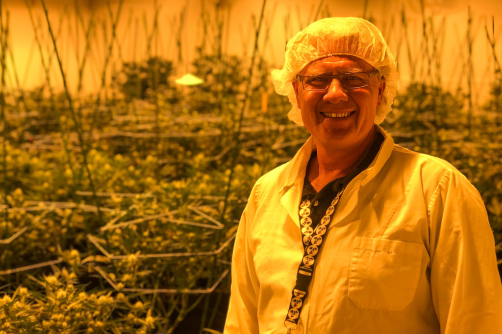 man in labcoat smiling at camera in marijuana farm lab