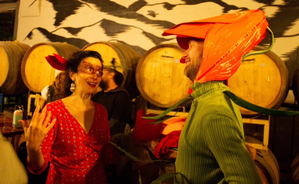 two people chat animatedly at a bar dressed up as two flowers