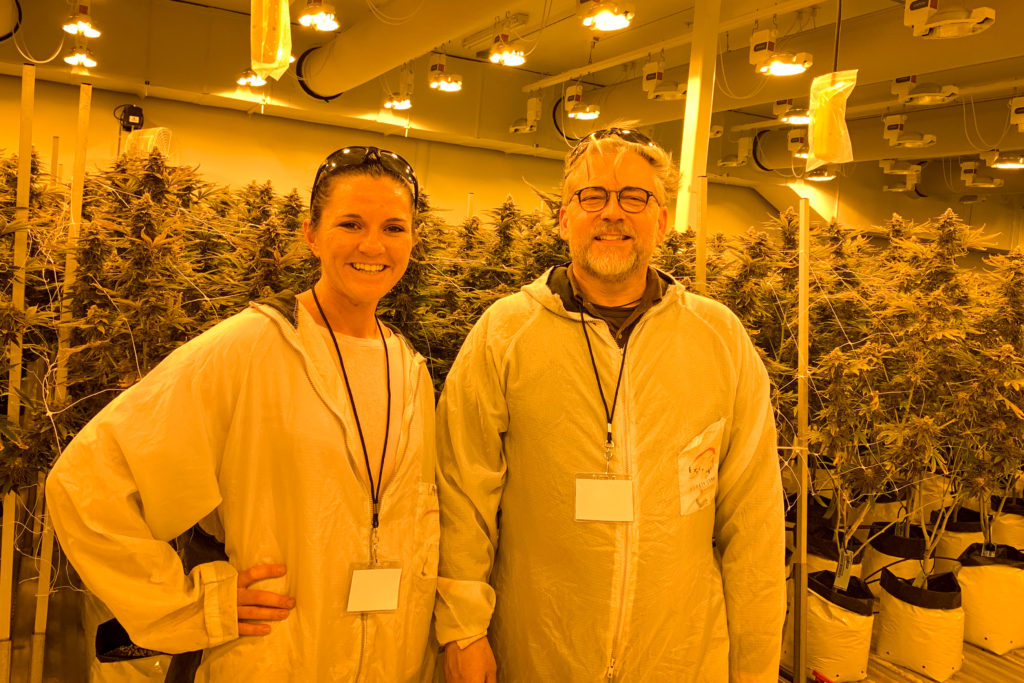 two people in labcoats smiling at camera in marijuana farm lab