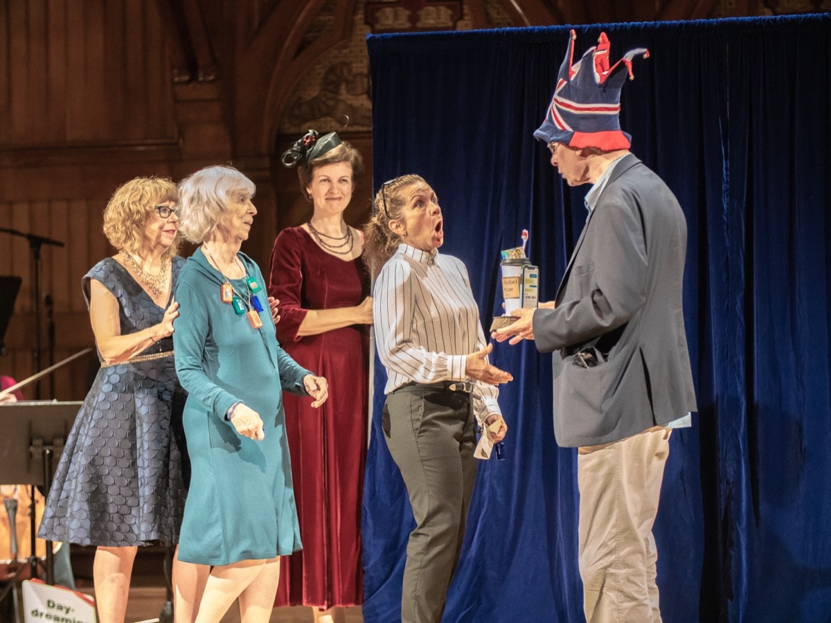 four women scientists on stage receiving an award from a man in a tall hat with england's flag on it