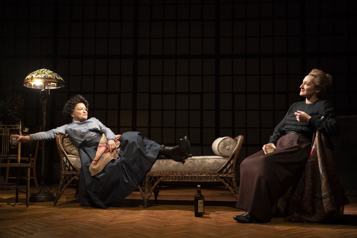 two women sit on chairs happily on stage