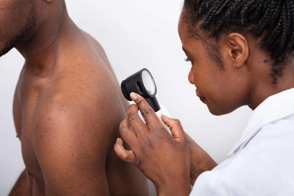 a black doctor inspecting a black patient's skin