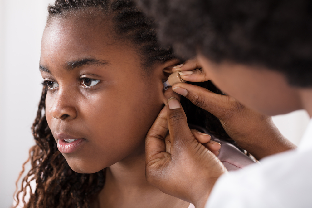 a doctor putting a hearing aid in a child's ear