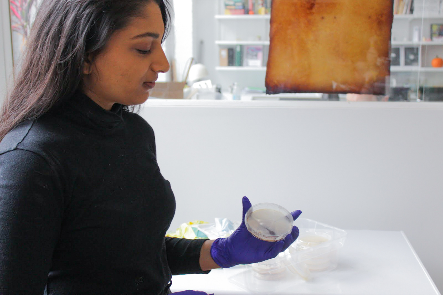 Woman holding up petri dish.