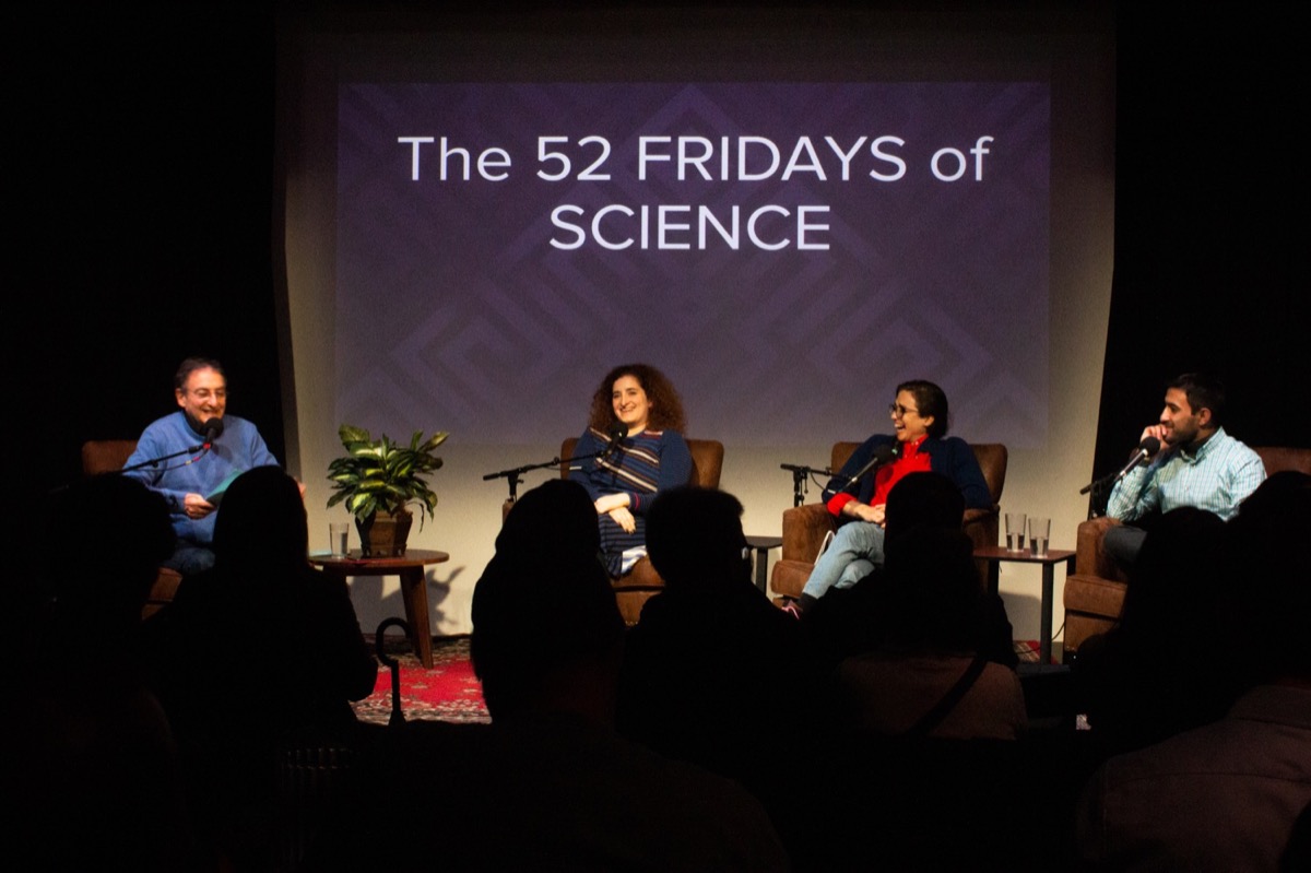 four people on stage in an interview with a slide in the background that reads "the 52 fridays of science"