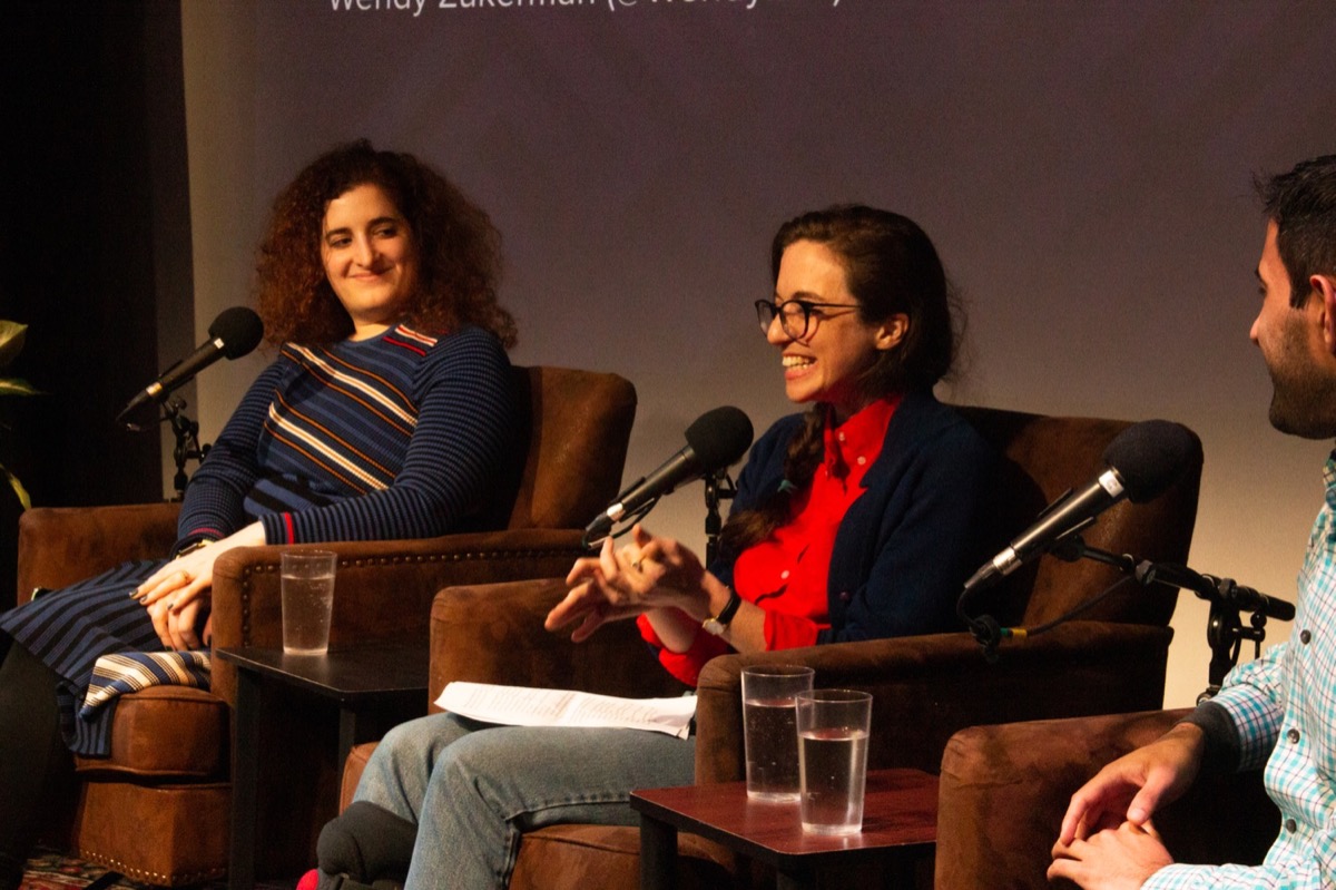 three people on stage laughing and talking