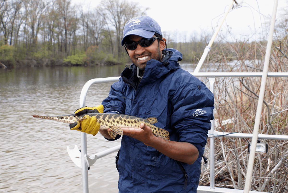 a man holds a spotted fish on a boat