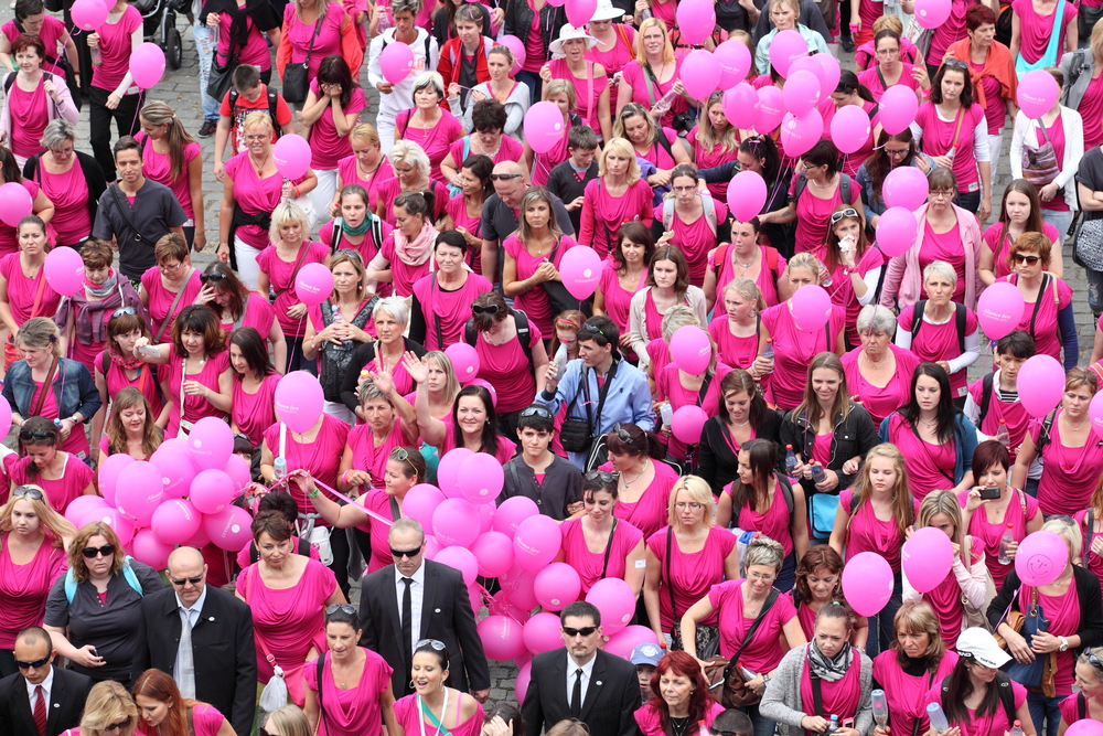 dozens of people in pink t-shirts with pink balloons