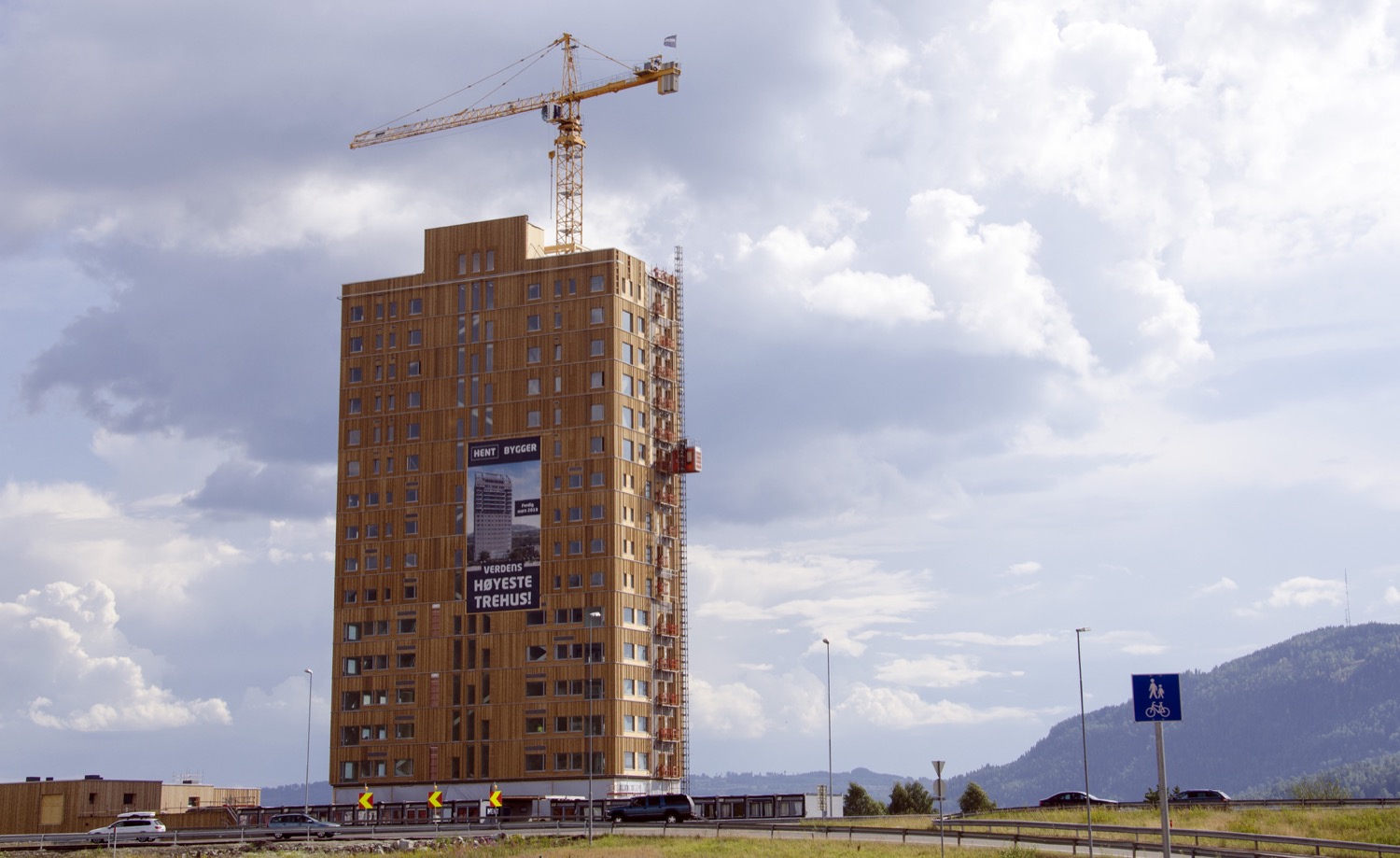 An 18-story tall wood building with a crane above it