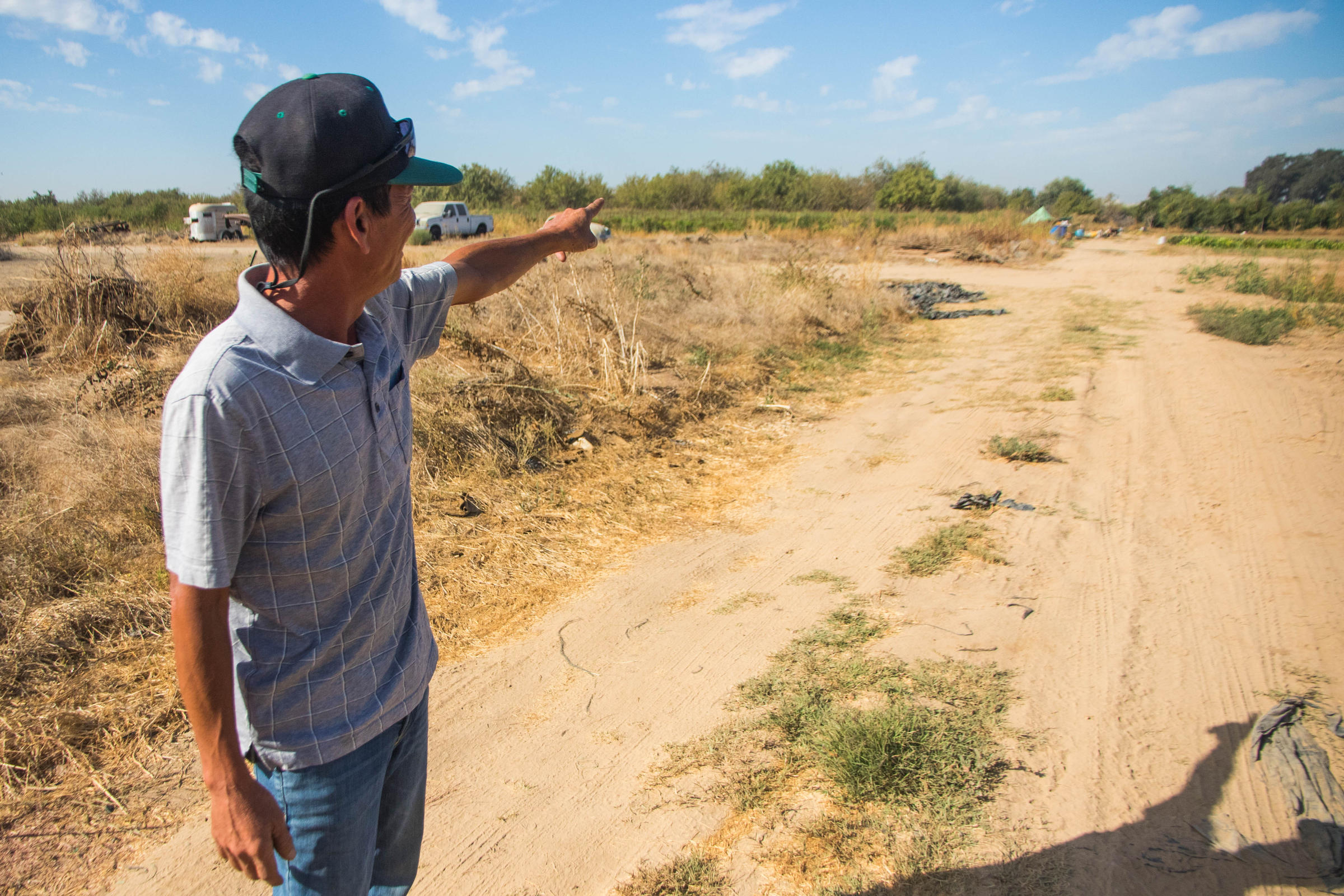 a man points off in the distance in a dirt farm