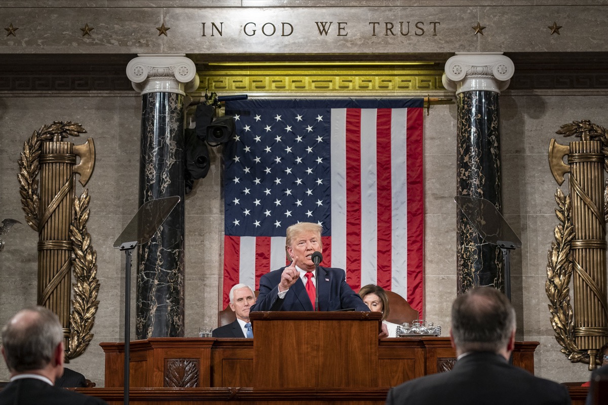 a man stands at a podium in front of the american flag