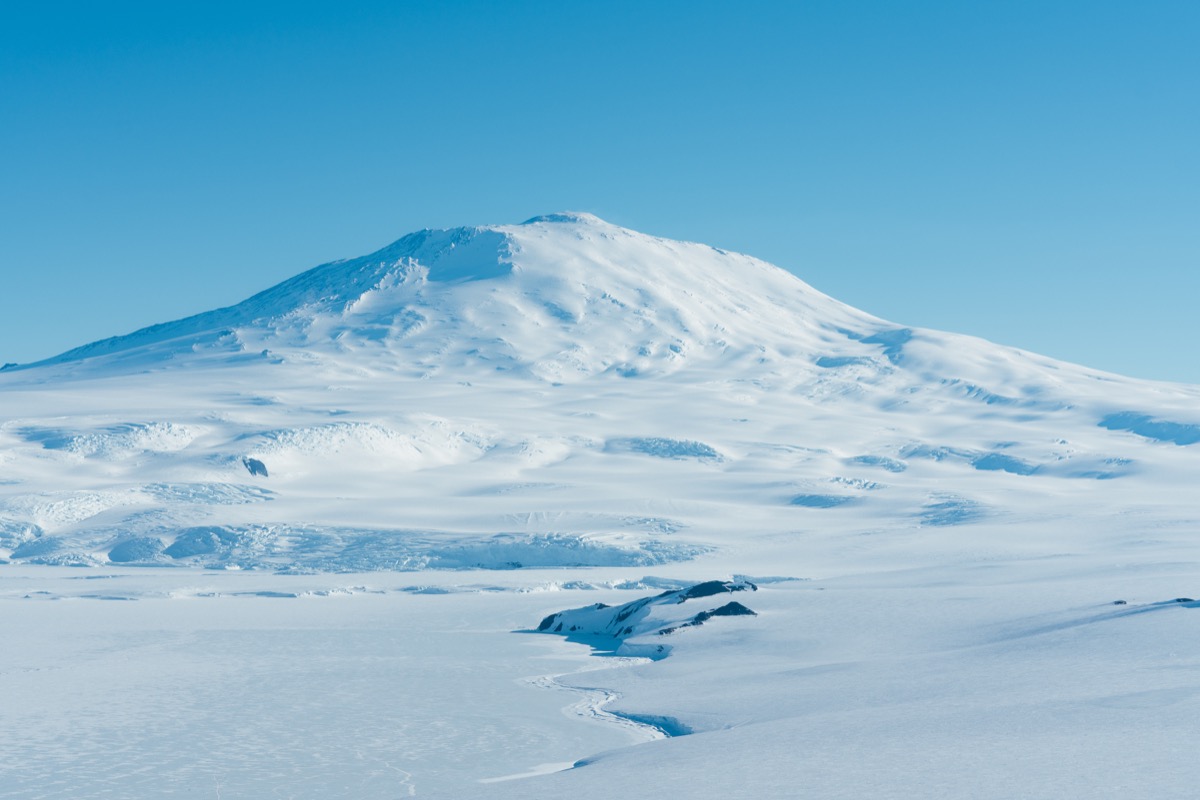 a completely ice covered terrain. a large mountain stands in the back
