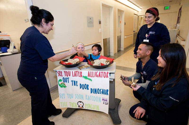 a group of people gather around a table that has sign that reads "see you later alligator" abraham sits behind the table.