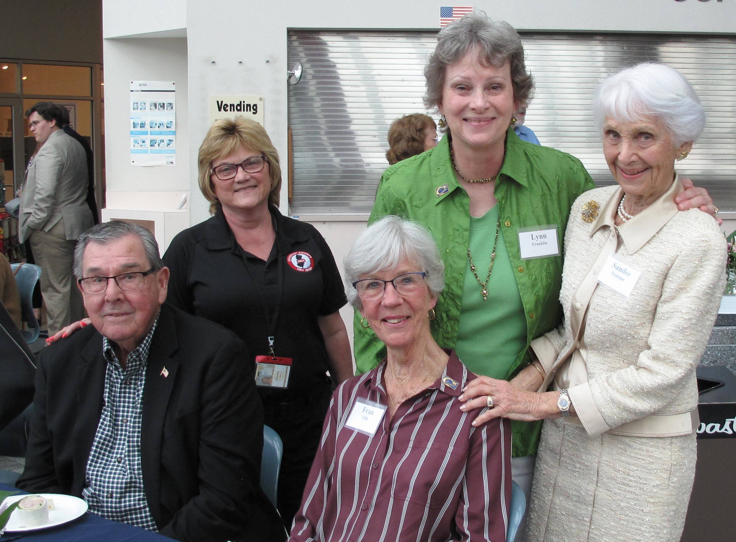 a group photo of four women and a man. standing in the middle in green is lynn franklin