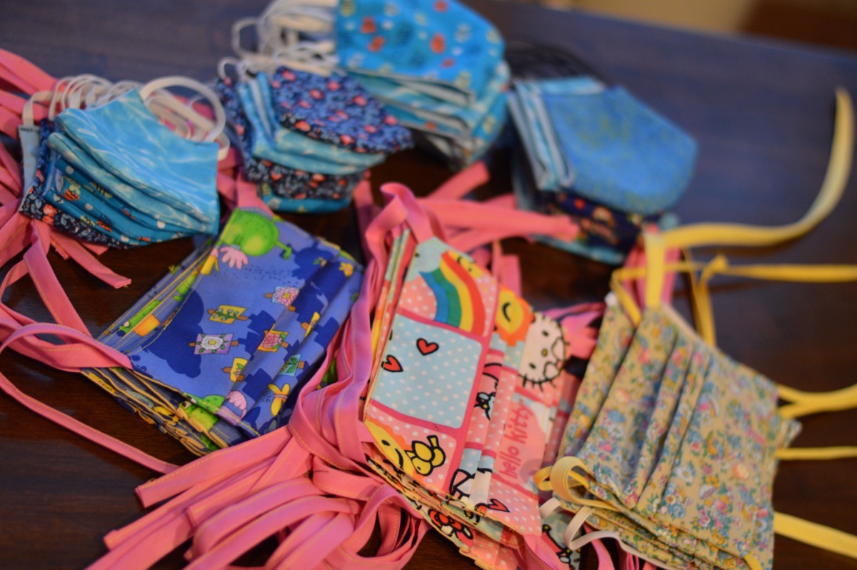 neat piles of homemade cloth medical masks, of various colorful prints and patters.