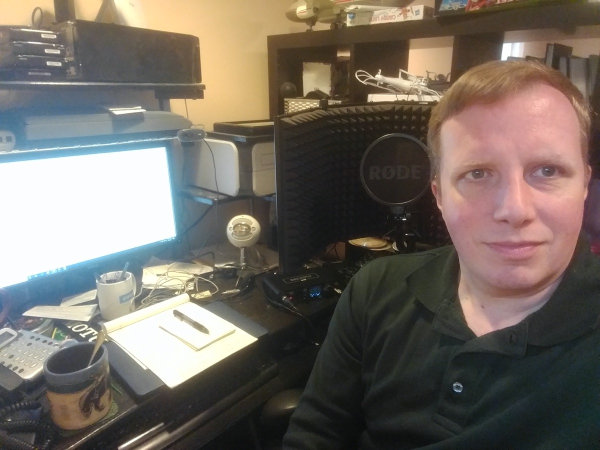 a man sitting next to an at-home recording studio set up in a basement