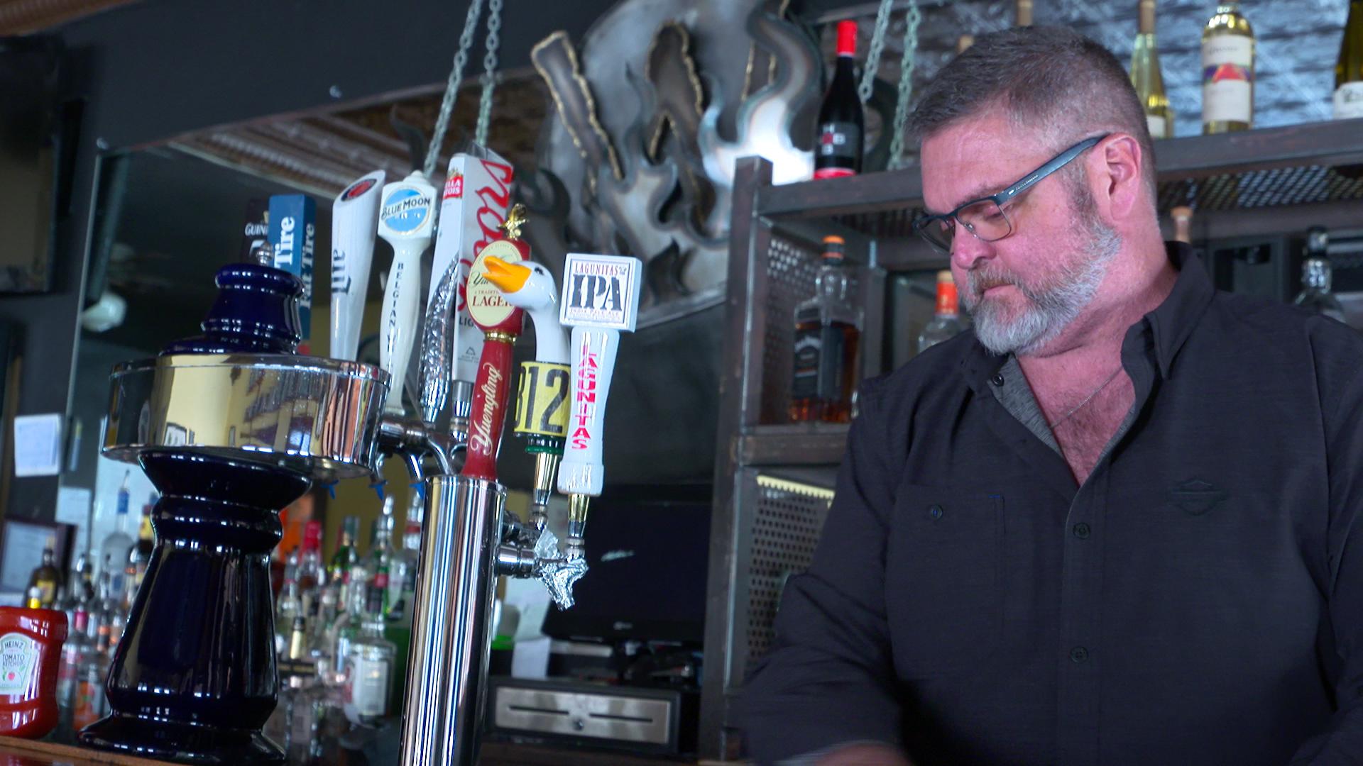 a man looking solemn behind a bar