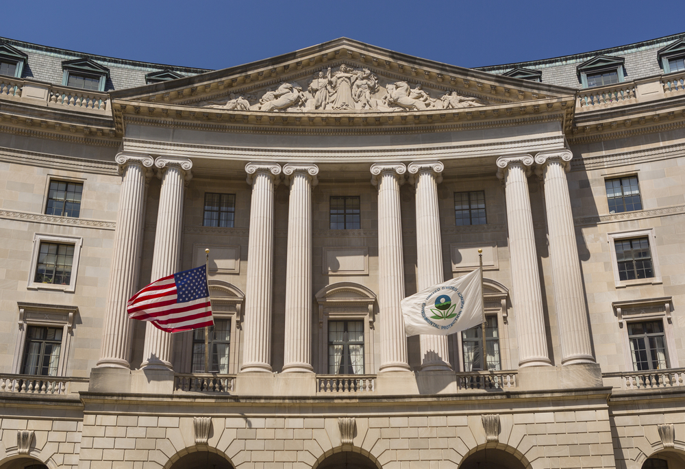 a white stone building with large pillars and an american flag and a white flag that shows the symbol of the environmental protection agency